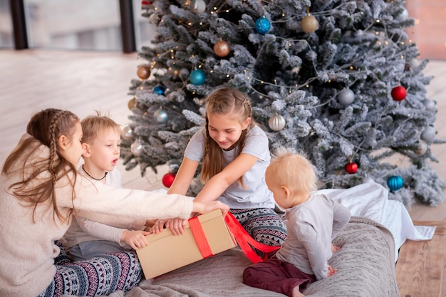 Gelukkige kinderen die plezier hebben en cadeautjes openen in de buurt van de kerstboom.