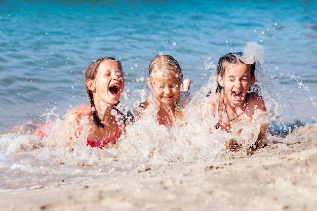 Gelukkige kinderen die plezier hebben met spelen met zeegolven op zandstrand Grappige kinderen zwemmen en spetteren