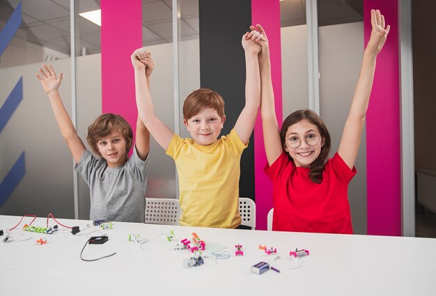 Gelukkige kinderen die samen robotica studeren in de klas