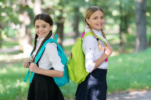 Gelukkige kinderen dragen schooltassen in formeel uniform buiten terug naar school