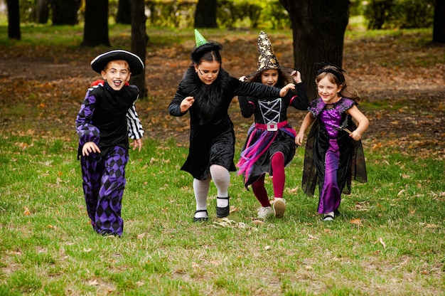 Gelukkige kinderen in halloween-kostuums die op het gazon lopen