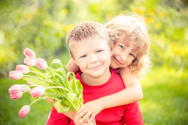 Gelukkige kinderen met boeket bloemen Jongen en meisje tegen groene achtergrond Lente familie vakantie concept Womens day