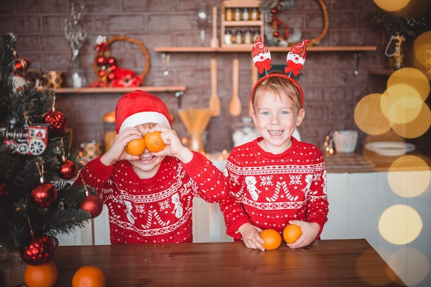 Gelukkige kinderen met sinaasappels in de donkere keuken thuis op kerstavond bereiden zich voor op de vakantie prettige kerstdagen en een vrolijk nieuwjaar