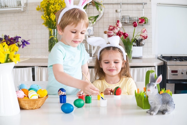 Foto gelukkige kinderen schilderen paaseieren in de keuken.