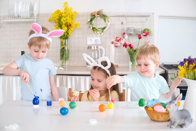Foto gelukkige kinderen schilderen paaseieren in de keuken.
