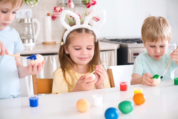 Foto gelukkige kinderen schilderen paaseieren in de keuken.