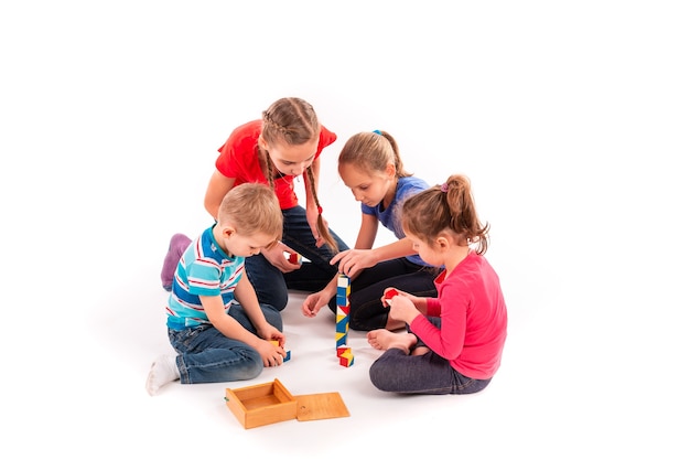 Gelukkige kinderen spelen met bouwstenen geïsoleerd op wit. Teamwerk, creativiteit concept.