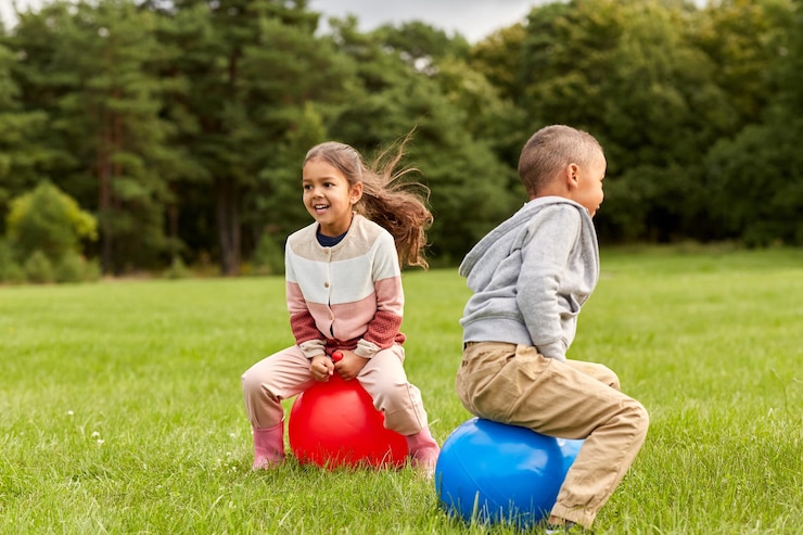 Foto gelukkige kinderen springen op hopperballen in het park.