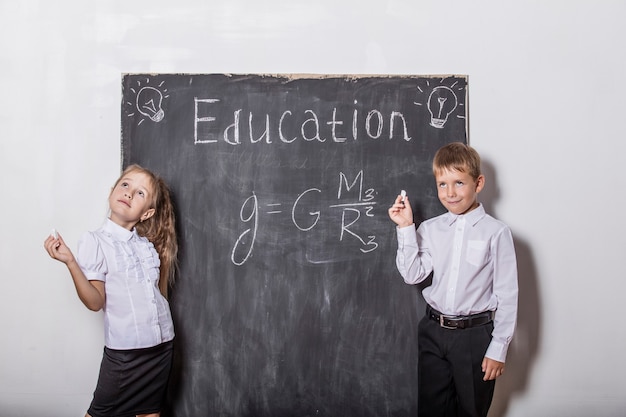 Gelukkige kinderen van de basisschool in de leisteen van de klasmuur