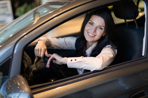 Gelukkige klantenvrouw die een nieuwe auto in dealeshipcentrum kopen.