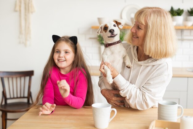 Gelukkige kleindochter en grootmoeder in de keuken met jack russell terrier hond oma en
