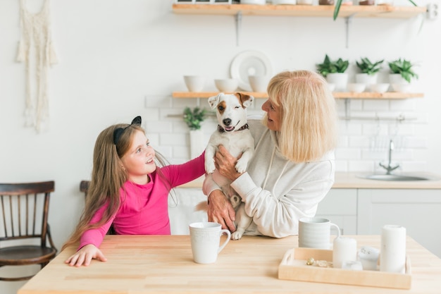 Gelukkige kleindochter en grootmoeder in de keuken met jack russell terrier hond oma en