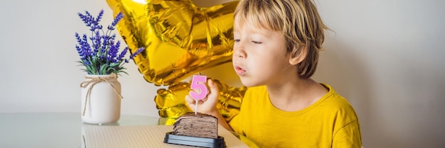 Gelukkige kleine jongen die zijn verjaardag viert en kaarsen blaast op zelfgemaakte gebakken cake binnen