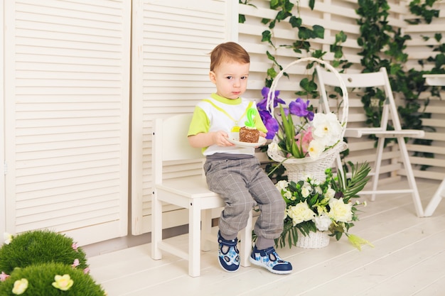 Gelukkige kleine jongen die zijn verjaardag viert, houdt een fluitje van een cent, binnen. Verjaardagsfeestje voor kinderen. Zorgeloze jeugd, geluk. Twee jaar oud.