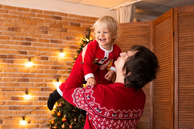 Gelukkige kleine jongen en vader spelen in feestelijk ingerichte kamer voor Kerstmis