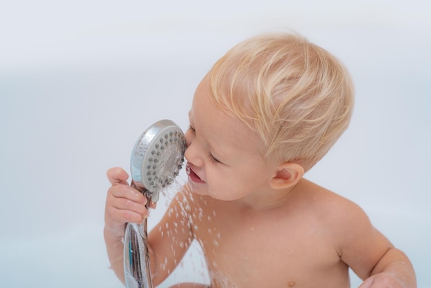 Gelukkige kleine jongen in bad Gelukkig lachende baby die een bad neemt en speelt met schuimbellen die mooi lacht