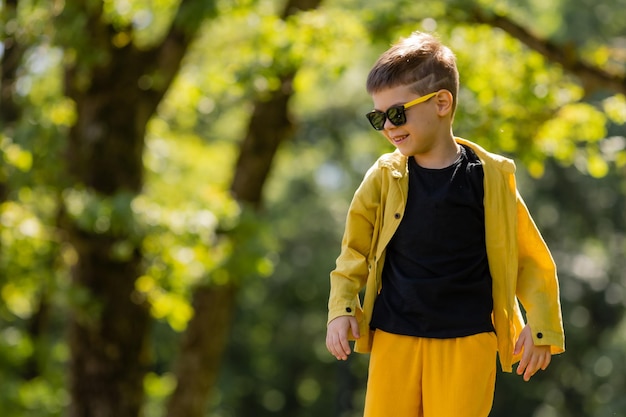 Gelukkige kleine jongen met zonnebril vangt zeepbellen in het park in de zomer