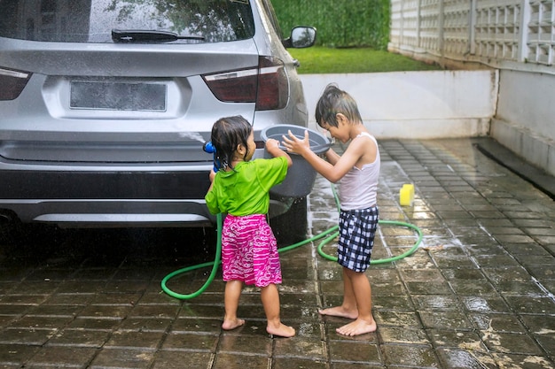 Gelukkige kleine kinderen die thuis een auto wassen.