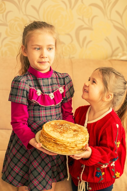 Foto gelukkige kleine meisjes met pannenkoekentwee grappige zussen