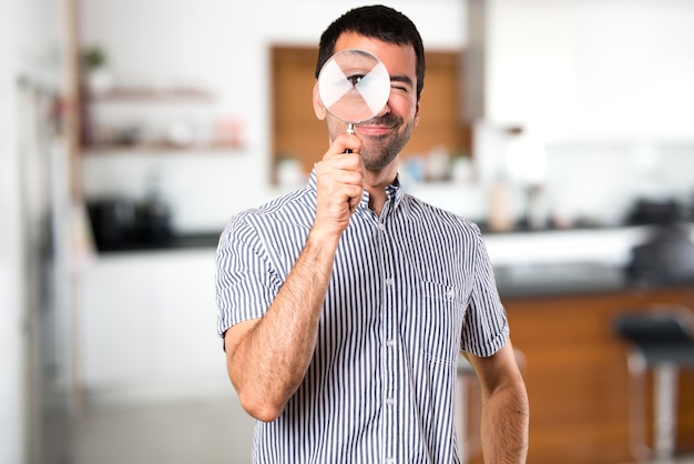 Gelukkige knappe man met vergrootglas in huis