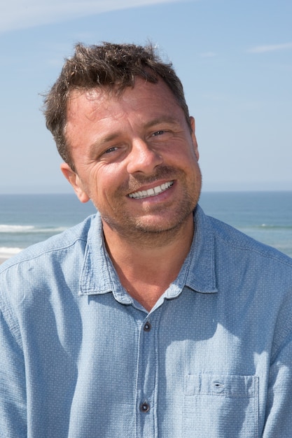 Foto gelukkige knappe mens die bij het strand glimlacht