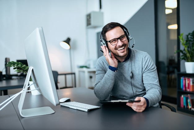 Gelukkige knappe technische ondersteuningsagent die aan een cliënt spreekt.