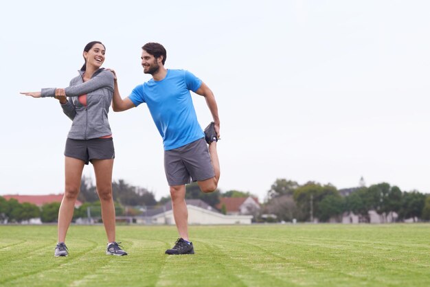 Gelukkige koppel fitness en stretching lichaam op groen gras voor outdoor workout of oefening in de natuur Actieve jonge man en vrouw in opwarmen samen voor training gezondheid en wellness op mockup ruimte