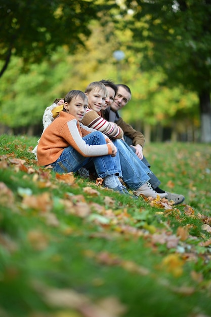 Gelukkige lachende familie zittend op bladeren in herfstbos