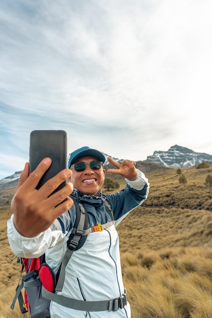 Gelukkige latijnse man-wandelaar die een selfie neemt op de bergrand in mexico