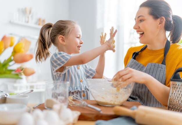 Gelukkige liefdevolle familie bereidt samen bakkerij voor. Moeder en kind dochter meisje koken koekjes en hebben plezier in de keuken. Zelfgemaakt eten en kleine helper.