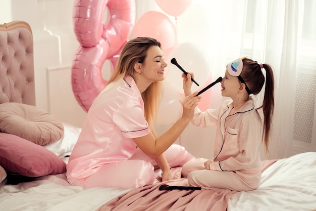 Gelukkige liefdevolle familie Moeder en dochter make-up spelen kus en knuffel