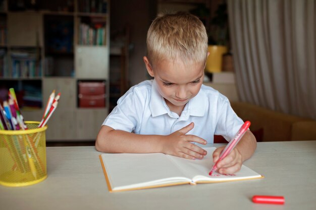 Gelukkige linkshandige jongen die in het papieren boek schrijft met zijn linkerhand internationale linkshandige dag