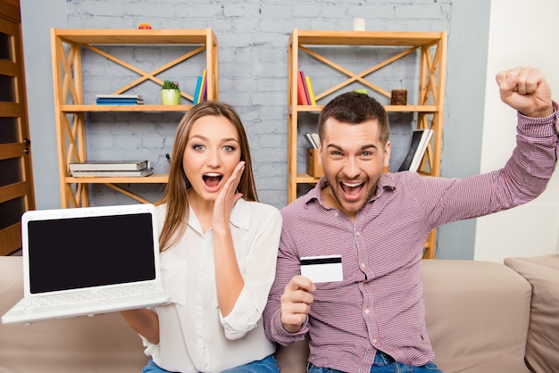 Gelukkige man en vrouw die met laptop en bankkaart gillen