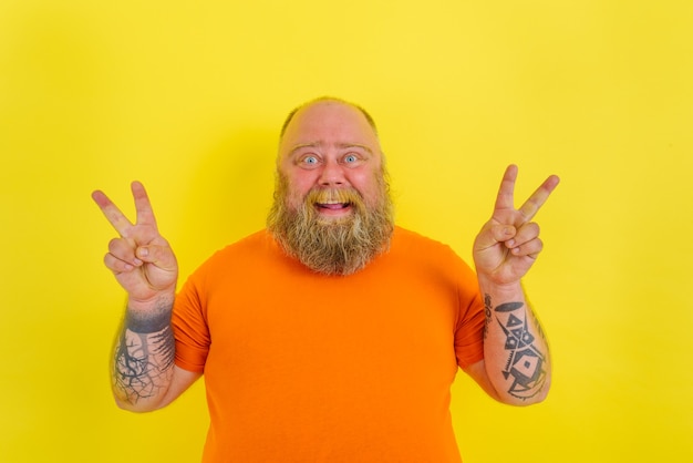 Foto gelukkige man met baard en tatoeages doet een winnend gebaar met handen