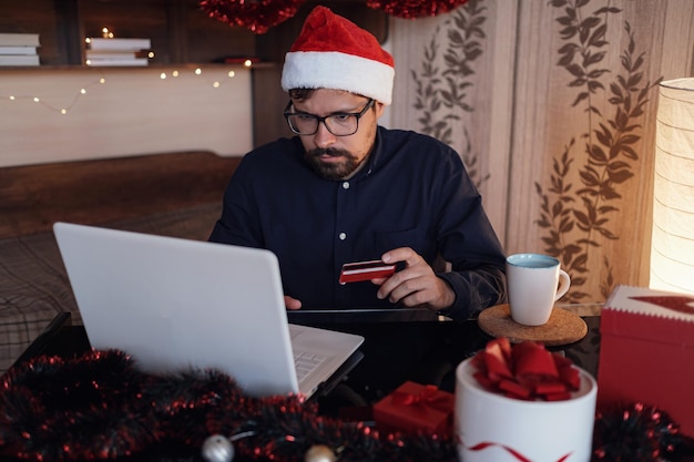 Gelukkige man met kerstmuts met cadeau of creditcard