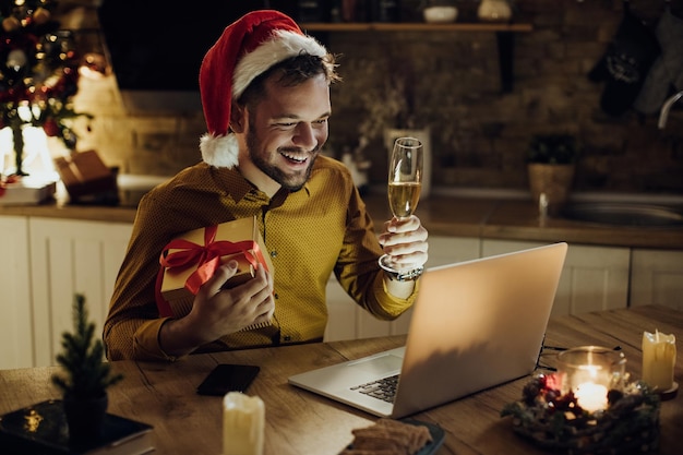 Gelukkige man roosteren met champagne tijdens videogesprek vanuit huis op kerstavond