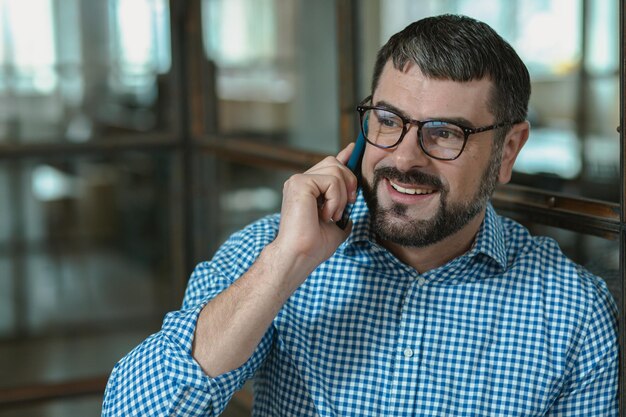 Foto gelukkige manager die een telefoongesprek voert op kantoor