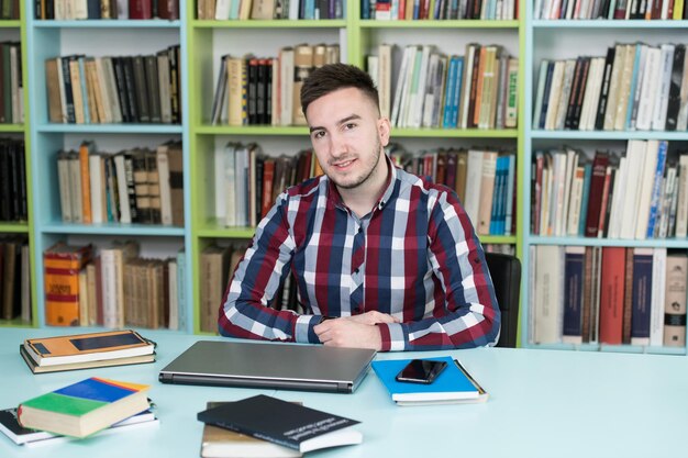 Foto gelukkige mannelijke student met laptop in bibliotheek
