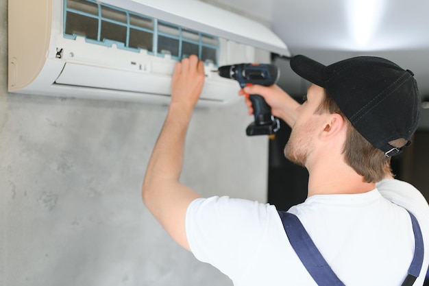 Gelukkige mannelijke technicus die airconditioner repareert