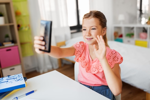 Gelukkige meisje met smartphone die thuis een selfie maakt.