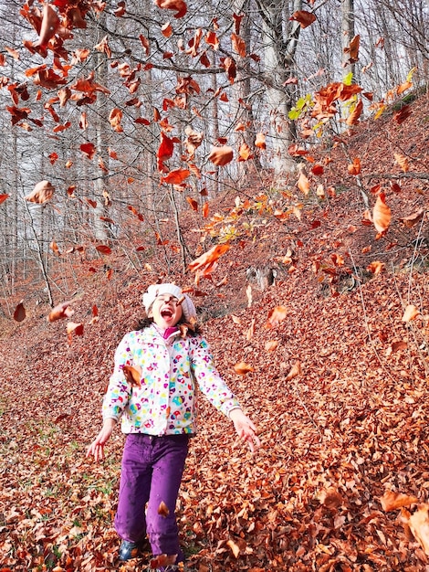 Foto gelukkige meisje speelt met bladeren in de herfst