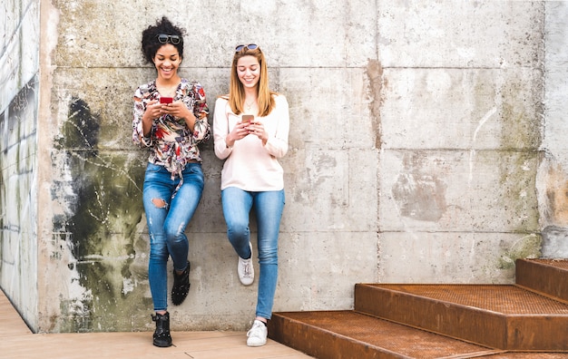 Gelukkige meisjes beste vrienden plezier buitenshuis met mobiele slimme telefoon