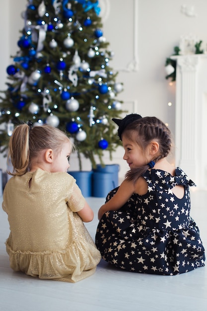 gelukkige meisjes die plezier hebben in de kersttijd zittend op de vloer