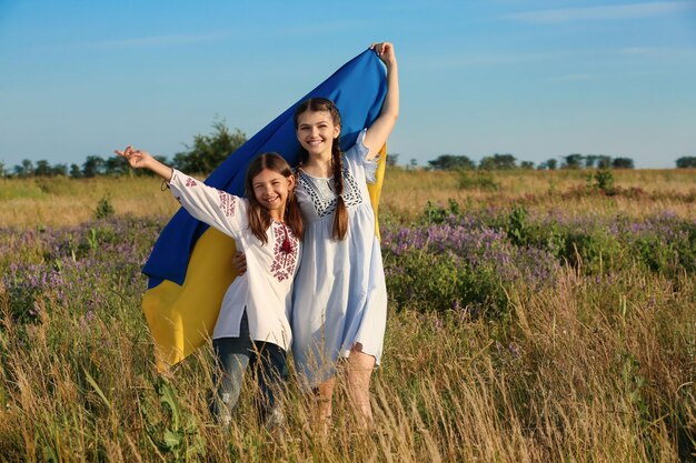 Foto gelukkige meisjes met de nationale vlag van oekraïne in het veld