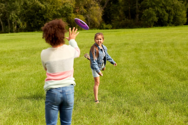 Foto gelukkige meisjes spelen met vliegende schijven in het park.