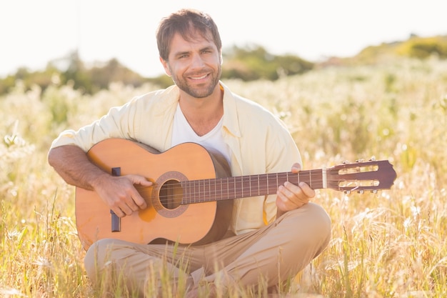 Gelukkige mens die en gitaar glimlacht speelt