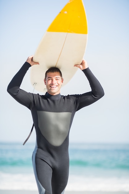 Foto gelukkige mens in wetsuit dragende surfplank lucht