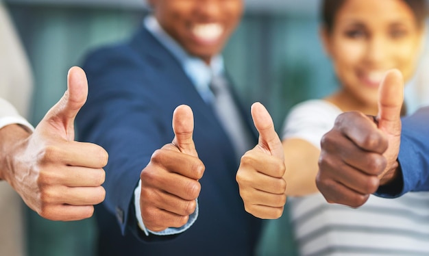 Gelukkige mensen en handen met duimen omhoog in het kantoor voor goedkeuring van overeenkomsten en teamwerk Medewerkers samenwerken en winnen voor partnerschap over een overeenkomst voor een project of taak met teambouw en eenheid