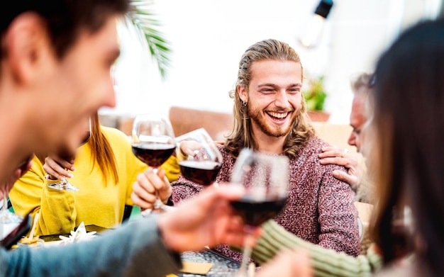 Gelukkige mensen met een oprechte stemming die rode wijn drinken op een feest op het dak millenial trendy vrienden die samen plezier hebben in de bar van de wijnmakerij van het restaurant dineren levensstijl concept met helder warm filter