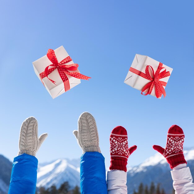 Gelukkige mensen overgeven de doos van de gift van Kerstmis tegen blauwe hemelachtergrond. Gelukkige paar plezier buiten in de winter. Kerst vakantie concept